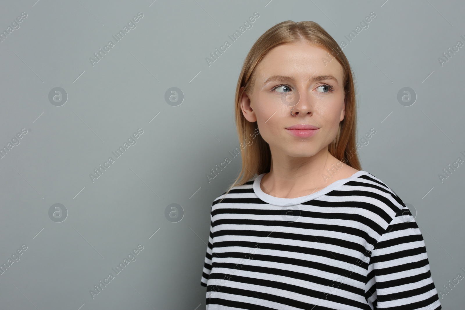 Photo of Portrait of beautiful young woman in striped t-shirt on grey background. Space for text