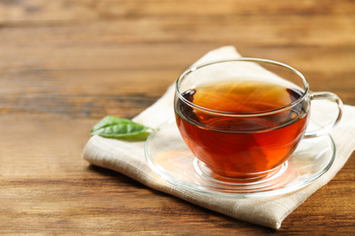 Photo of Cup of black tea on wooden table. Space for text