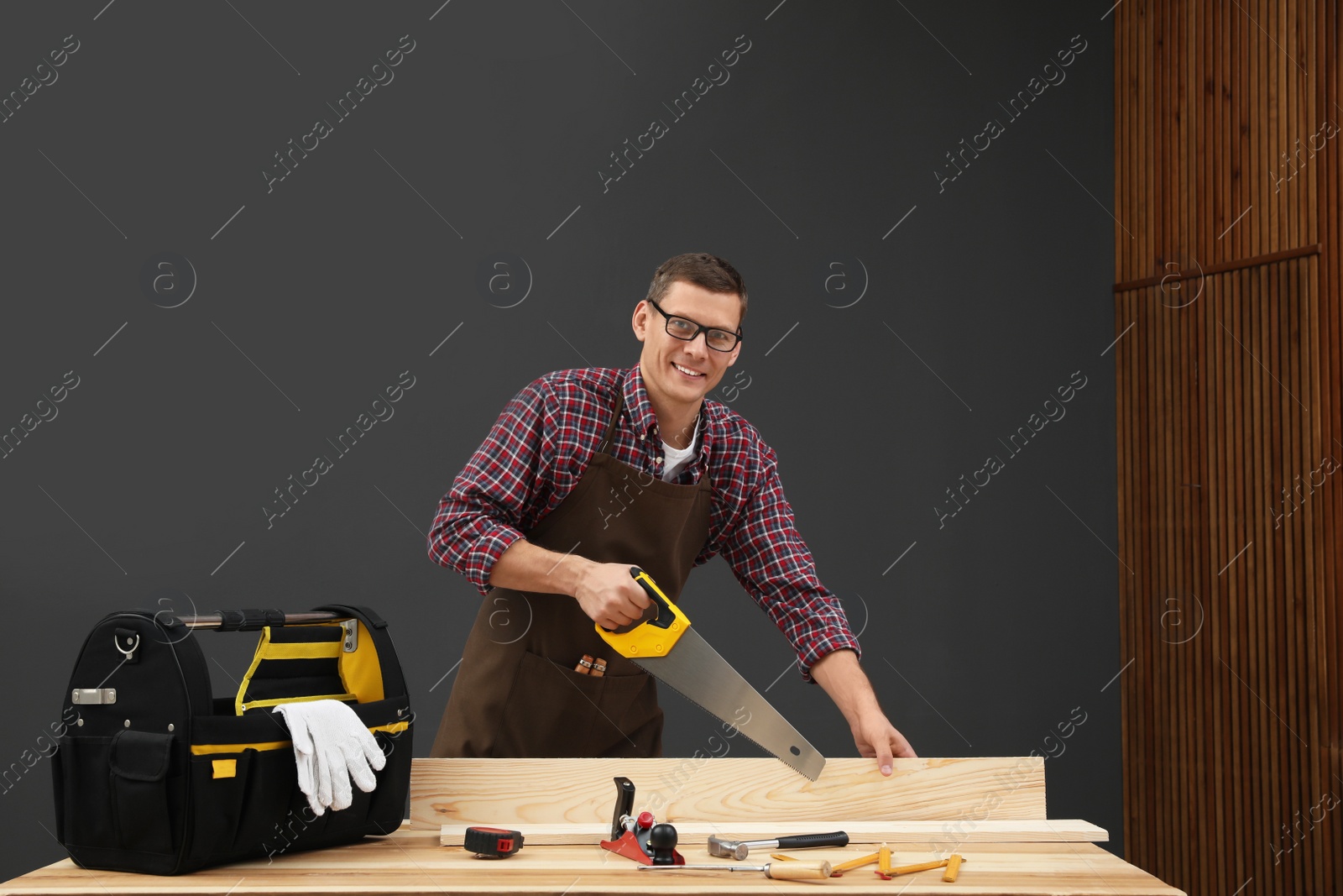 Photo of Carpenter working with hand saw at table indoors