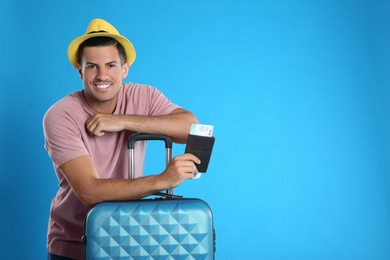 Photo of Man with suitcase and ticket in passport for summer trip on blue background. Vacation travel