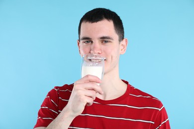 Milk mustache left after dairy product. Man drinking milk on light blue background