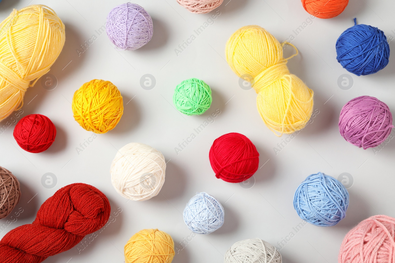 Photo of Soft colorful woolen yarns on white background, flat lay