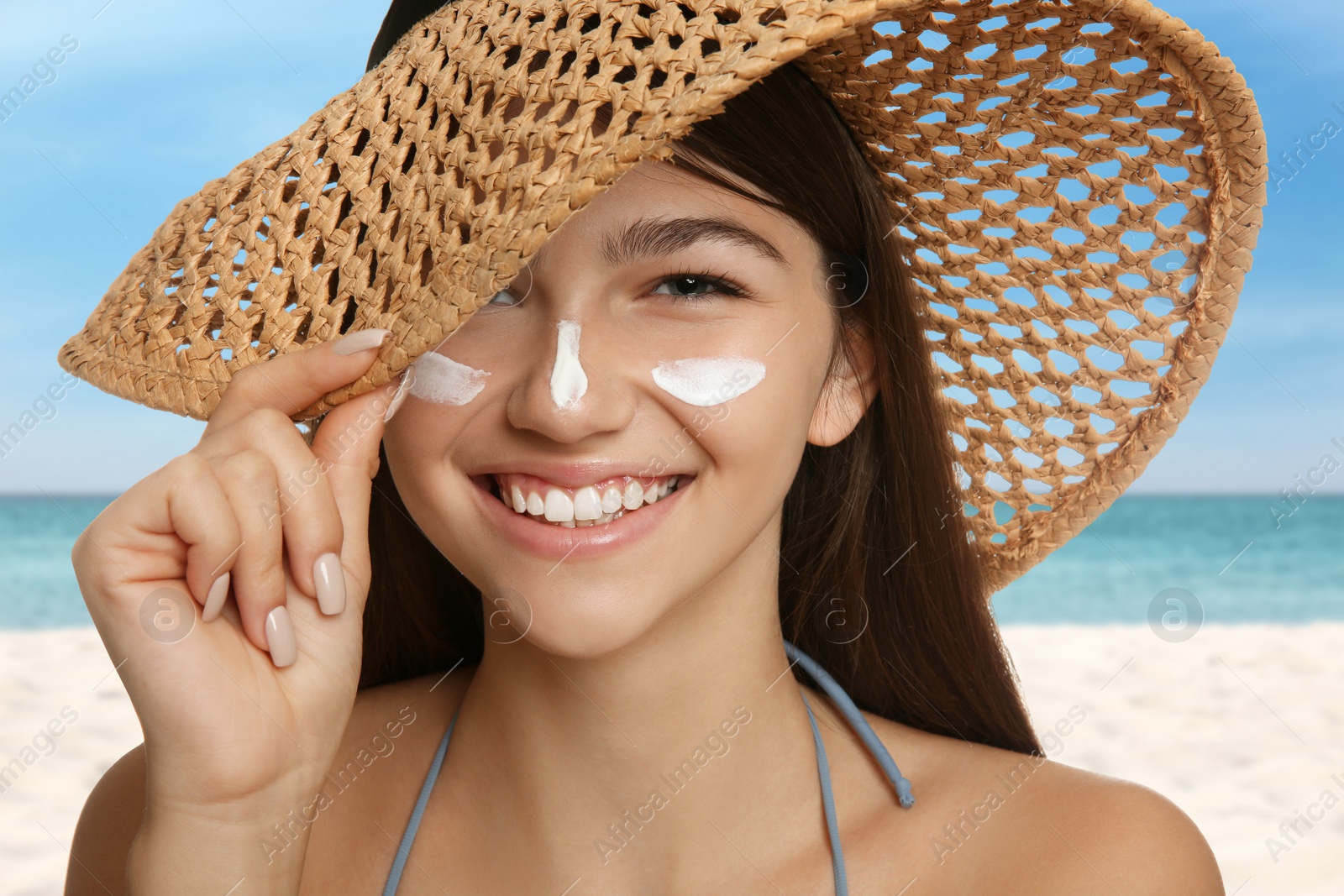 Image of Teenage girl with sun protection cream on her face near sea 