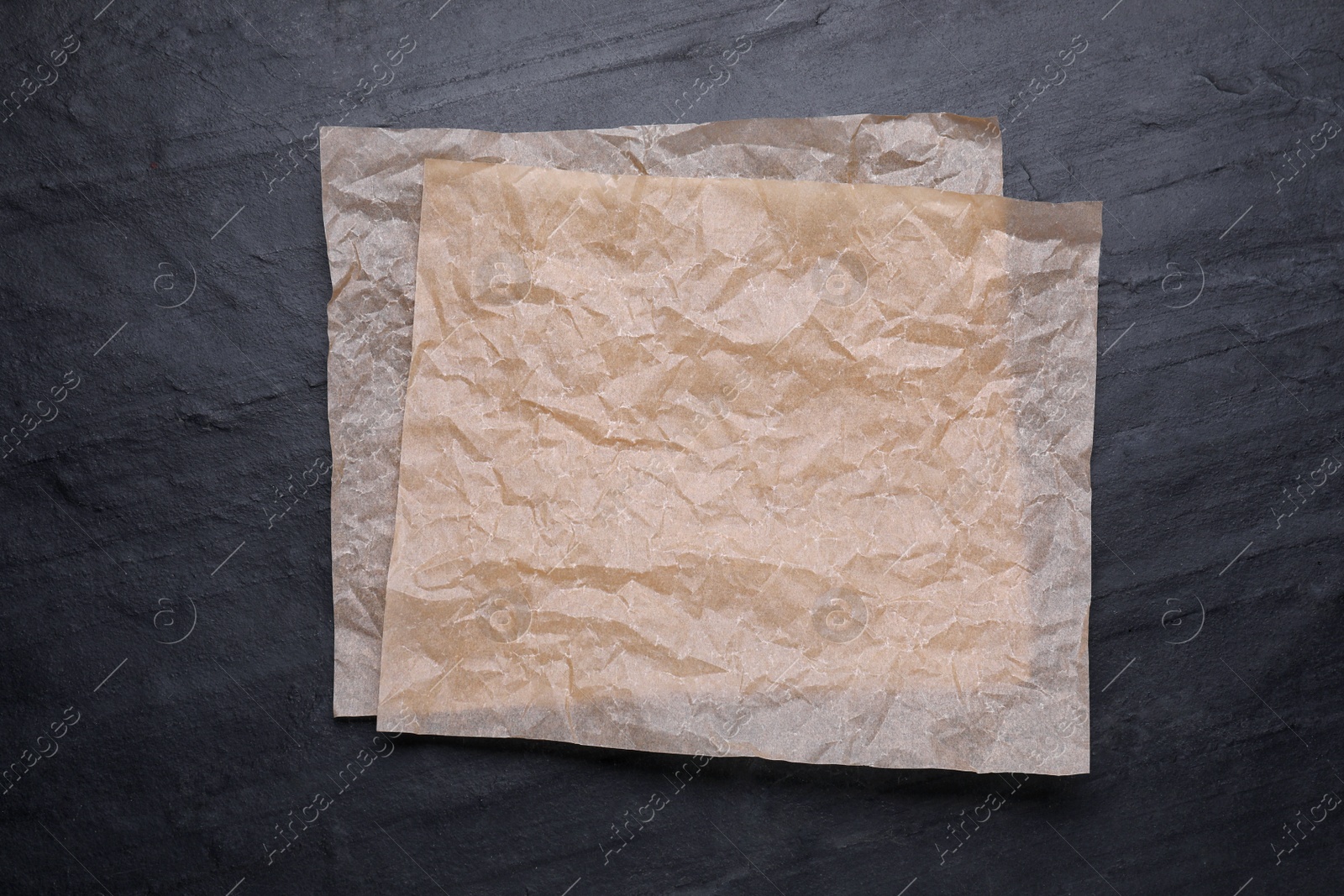 Photo of Sheets of baking paper on black table, top view