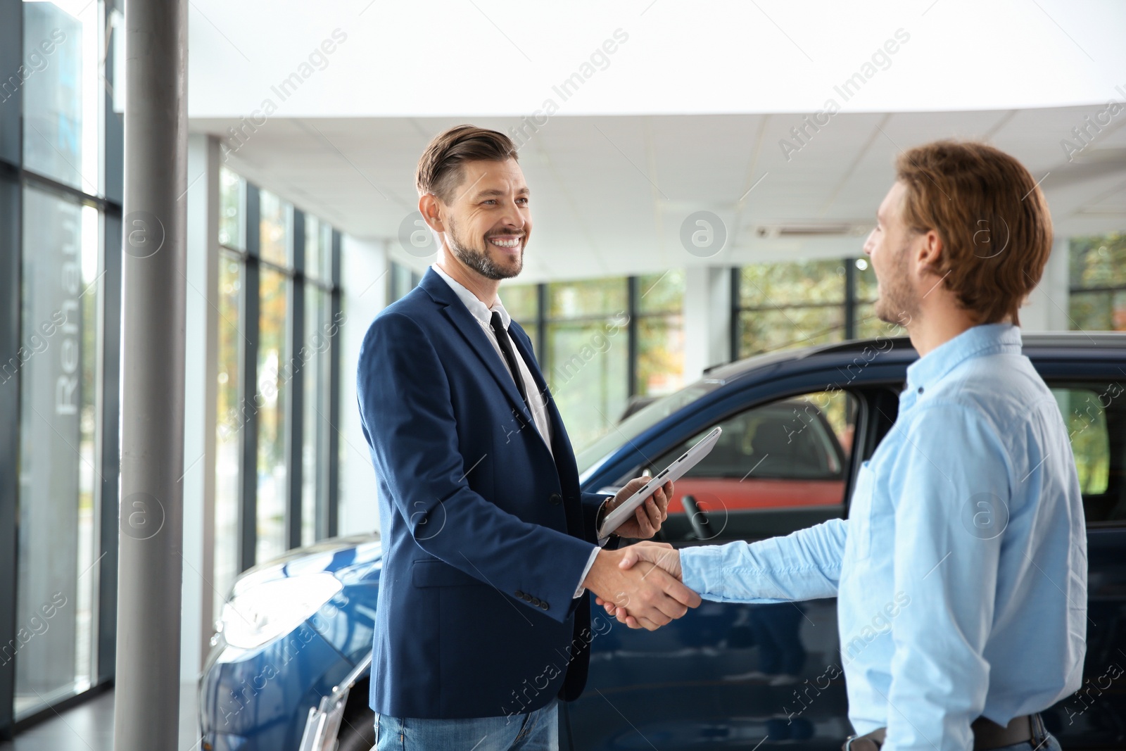 Photo of Customer and salesman shaking hands in car dealership