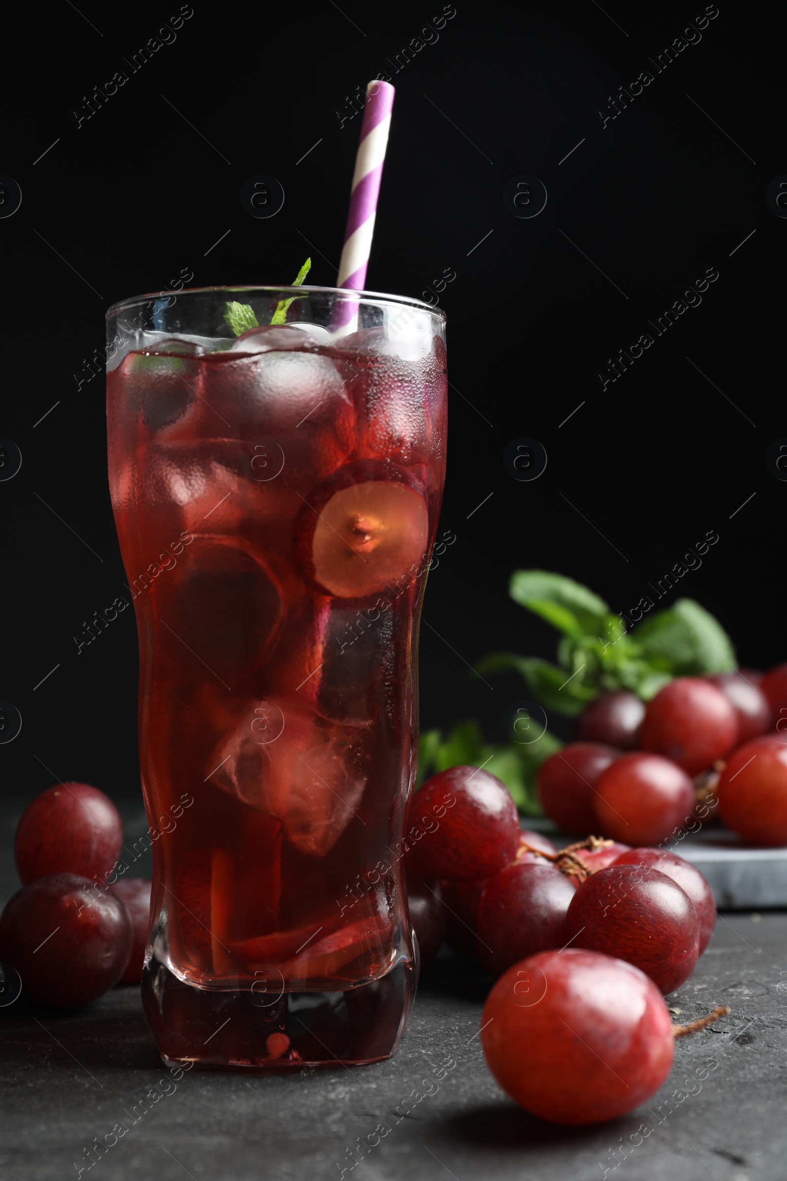 Photo of Delicious grape soda water on black table. Refreshing drink