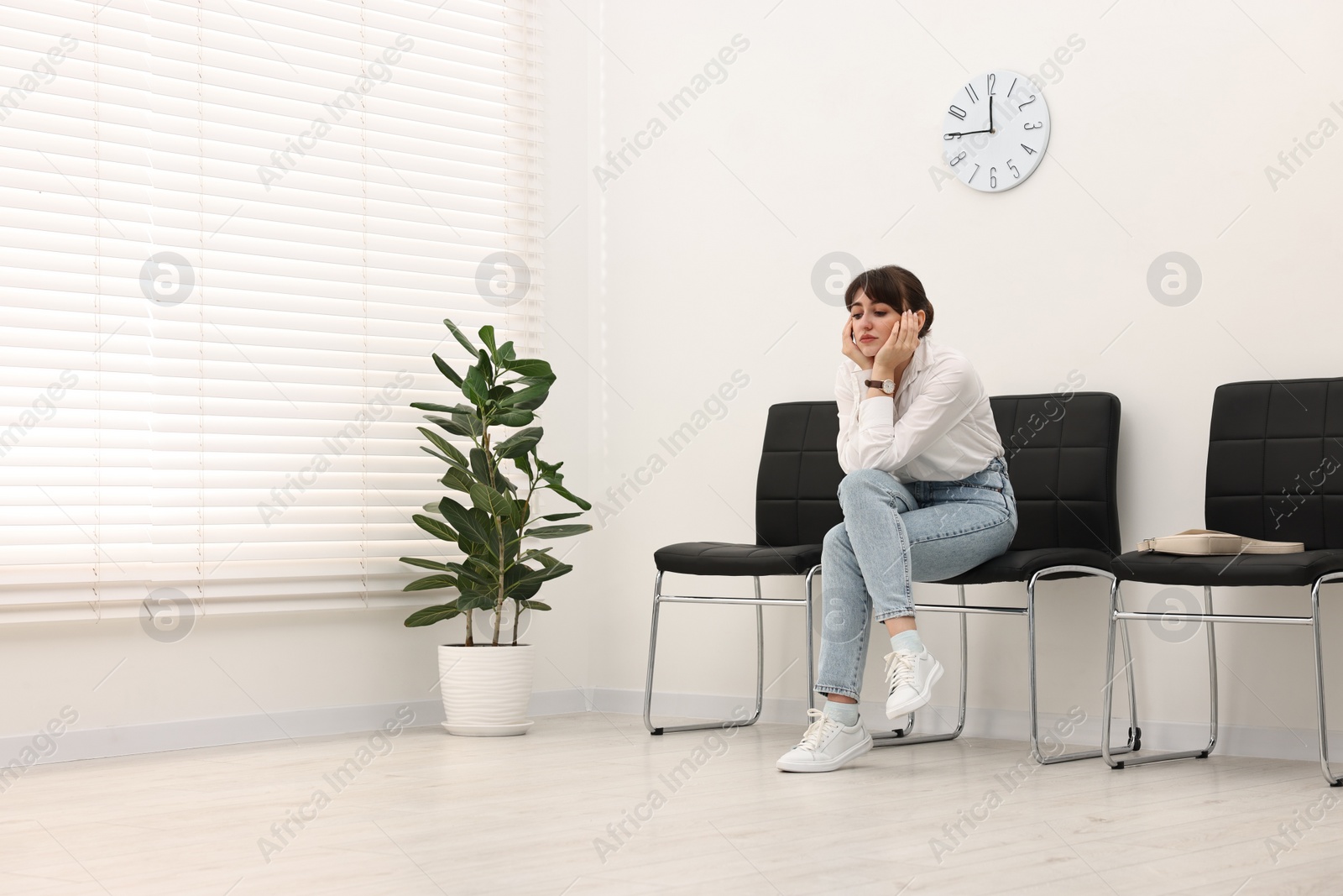 Photo of Woman sitting on chair and waiting for appointment indoors