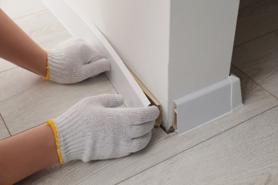 Photo of Man installing plinth on laminated floor in room, closeup