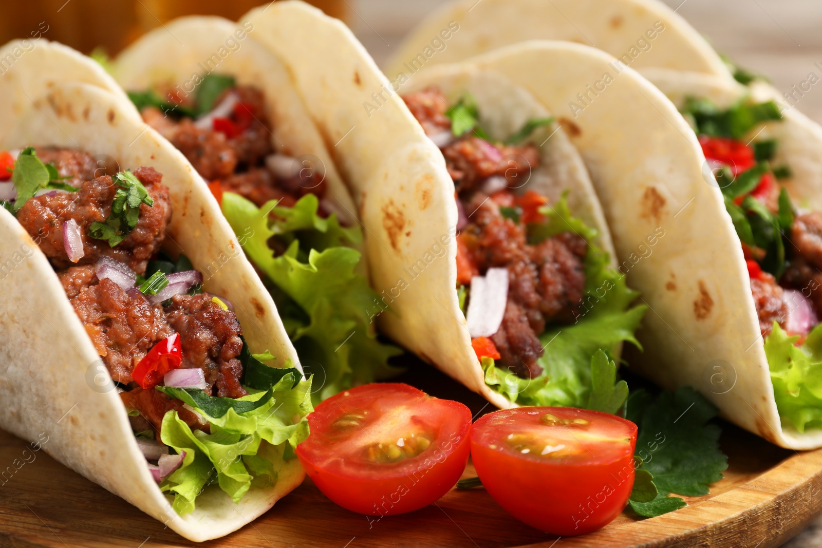 Photo of Delicious tacos with meat and vegetables on table, closeup