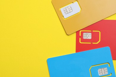 Photo of Different SIM cards on yellow background, flat lay. Space for text