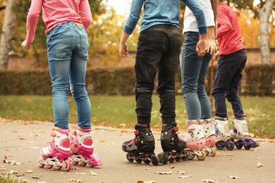 Photo of Children roller skating in autumn park, focus on legs