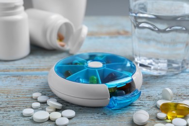 Photo of Pill box with medicaments on wooden table, closeup