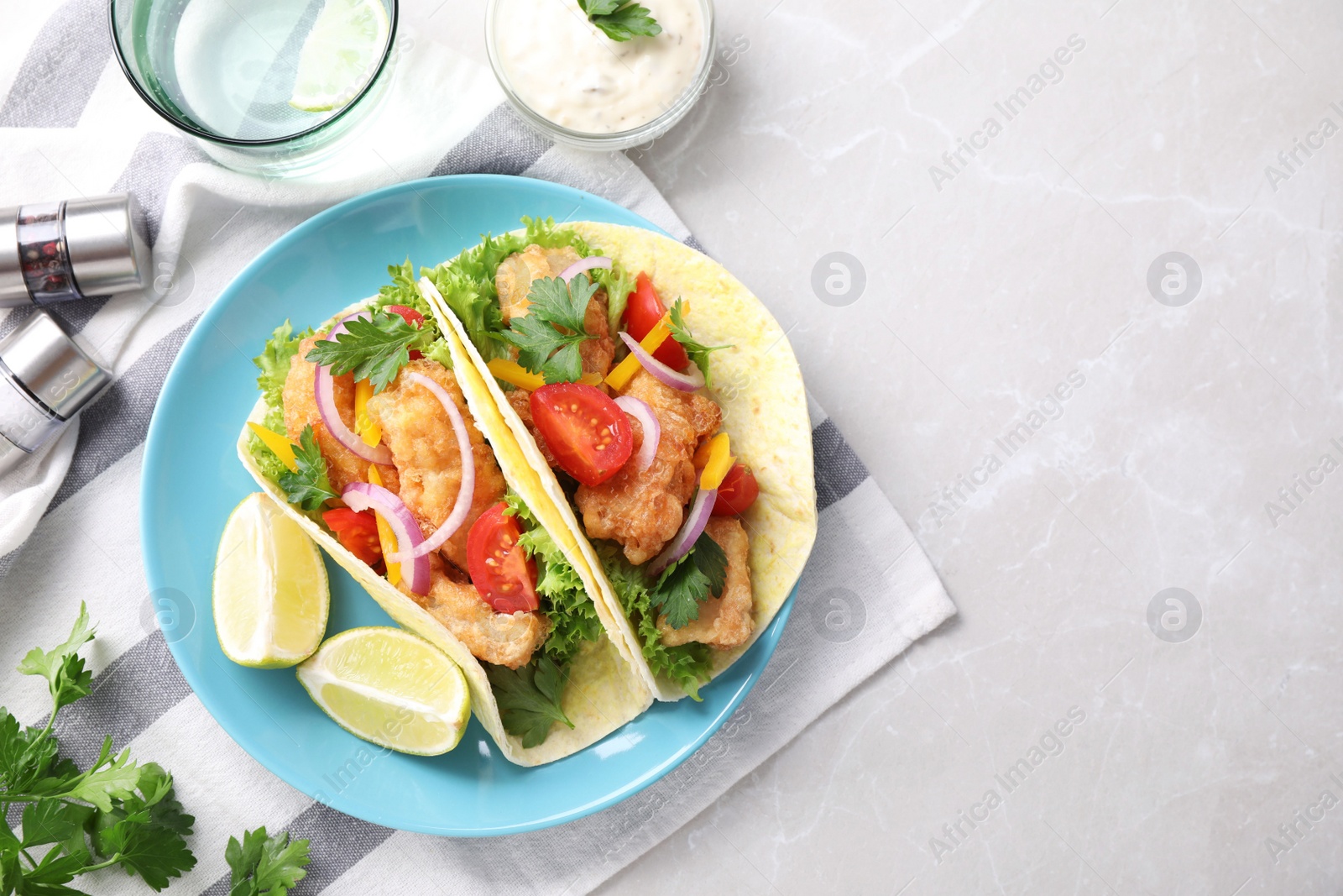 Photo of Yummy fish tacos served on marble table, flat lay. Space for text