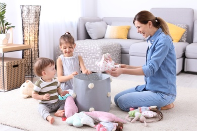 Photo of Housewife and children picking up toys after playing at home