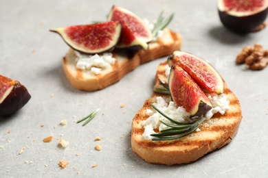 Photo of Bruschettas with ripe figs and cheese on light table, closeup