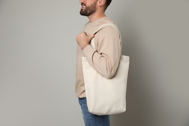 Photo of Happy young man with eco bag on light background, closeup