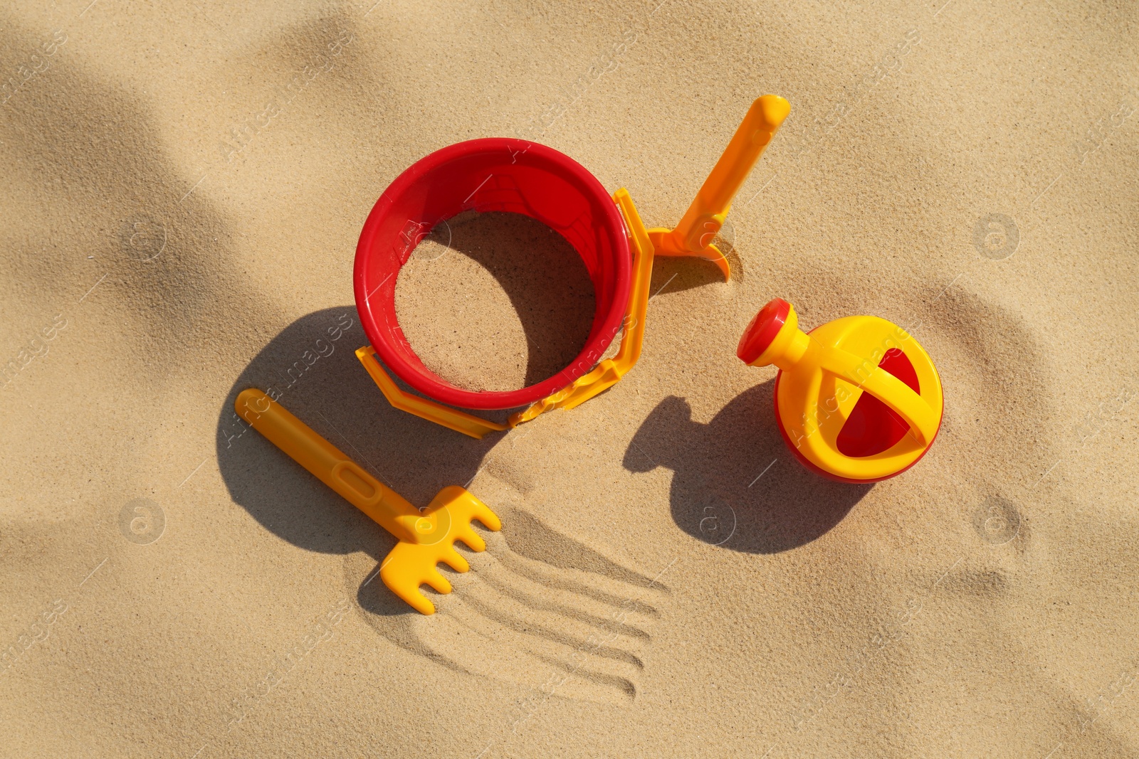 Photo of Set of plastic beach toys on sand, flat lay. Outdoor play