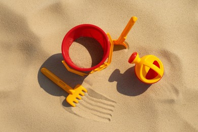 Photo of Set of plastic beach toys on sand, flat lay. Outdoor play