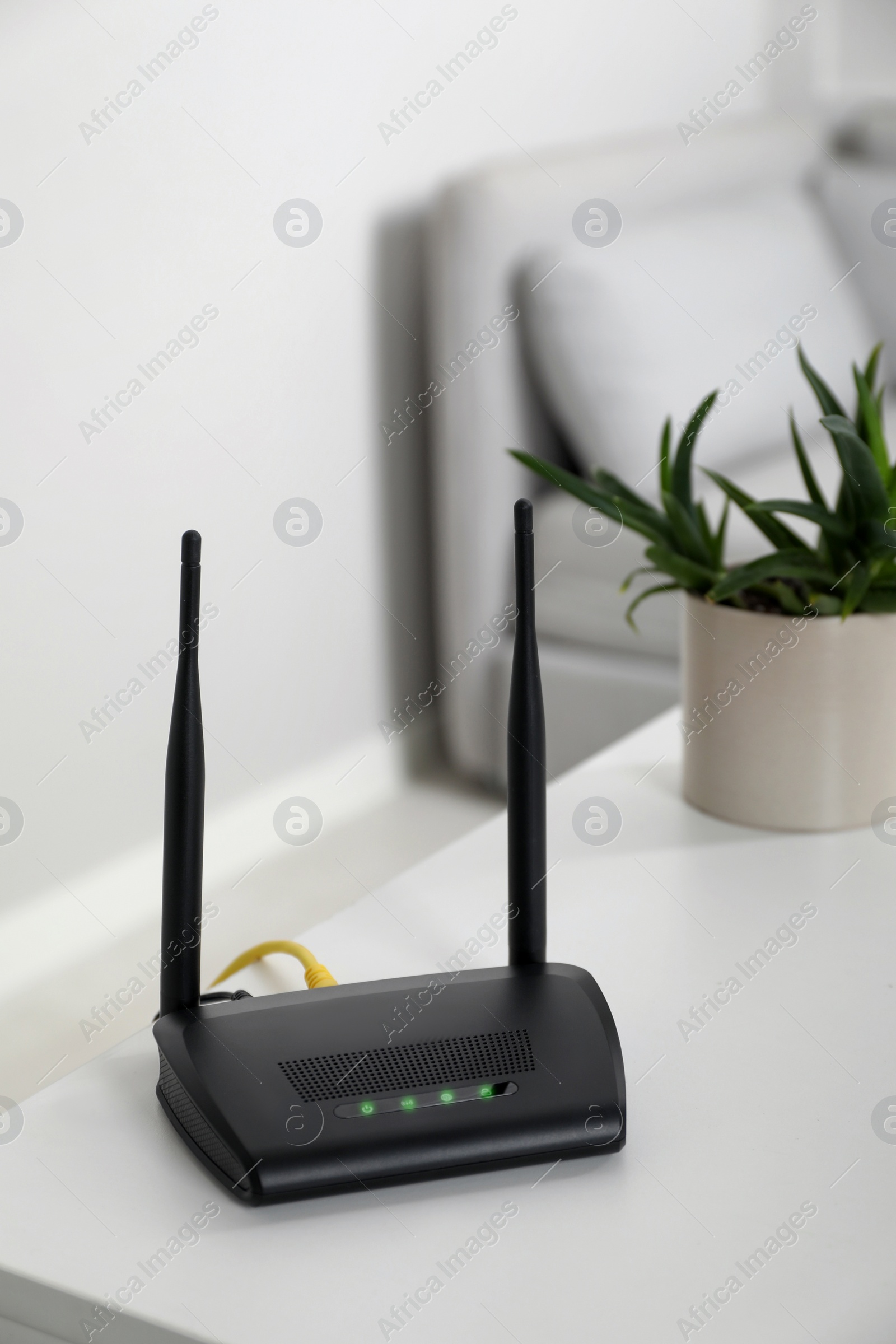 Photo of Modern Wi-Fi router on white table in room