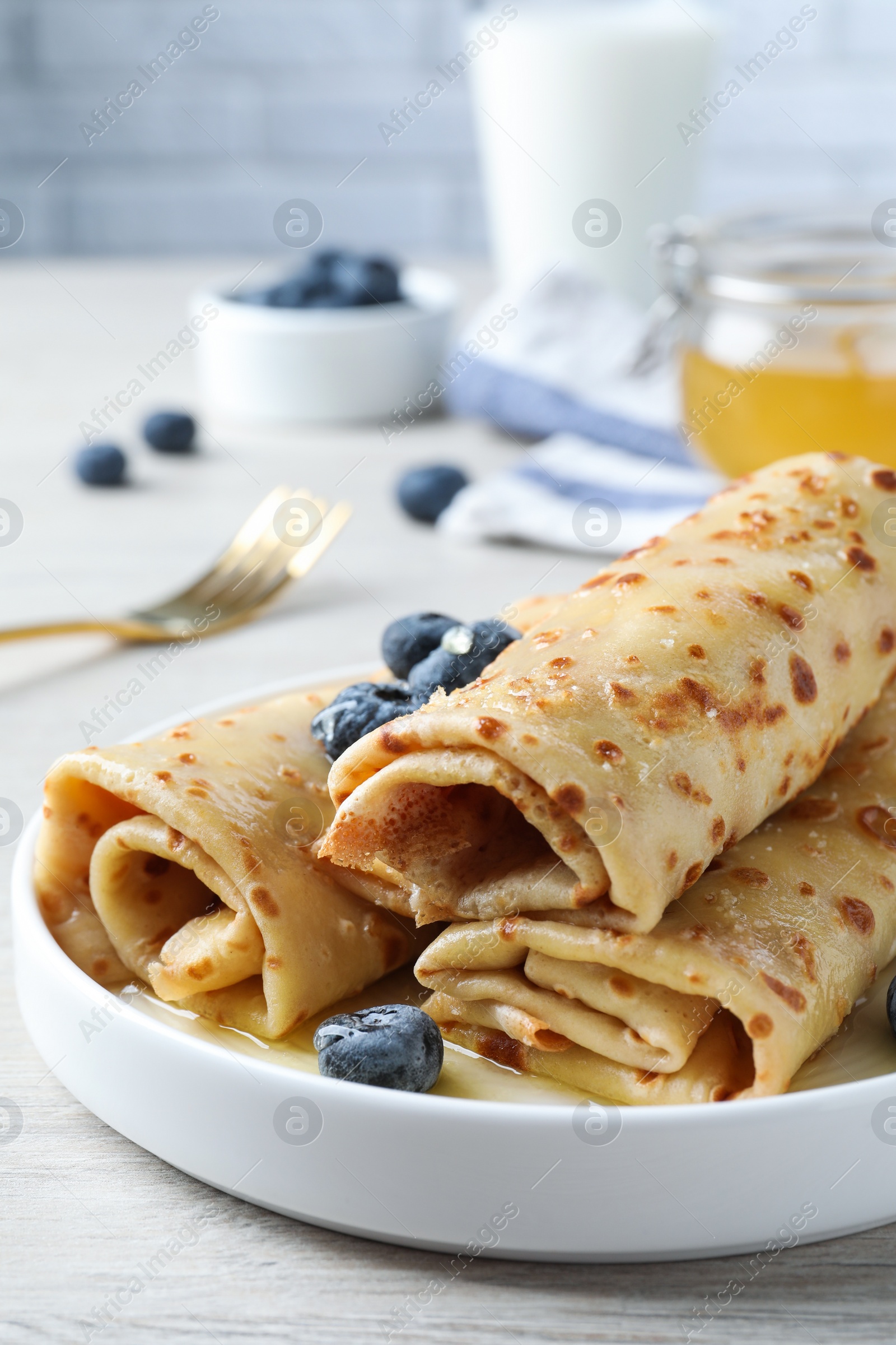 Photo of Delicious crepes with blueberries on white wooden table, closeup