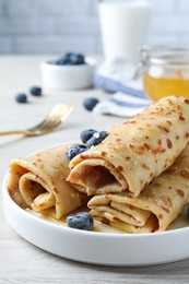 Photo of Delicious crepes with blueberries on white wooden table, closeup