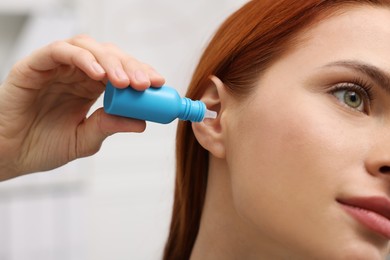 Photo of Woman applying medical ear drops at home, closeup