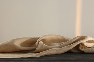 Natural burlap fabric on wooden table against light background. Space for text