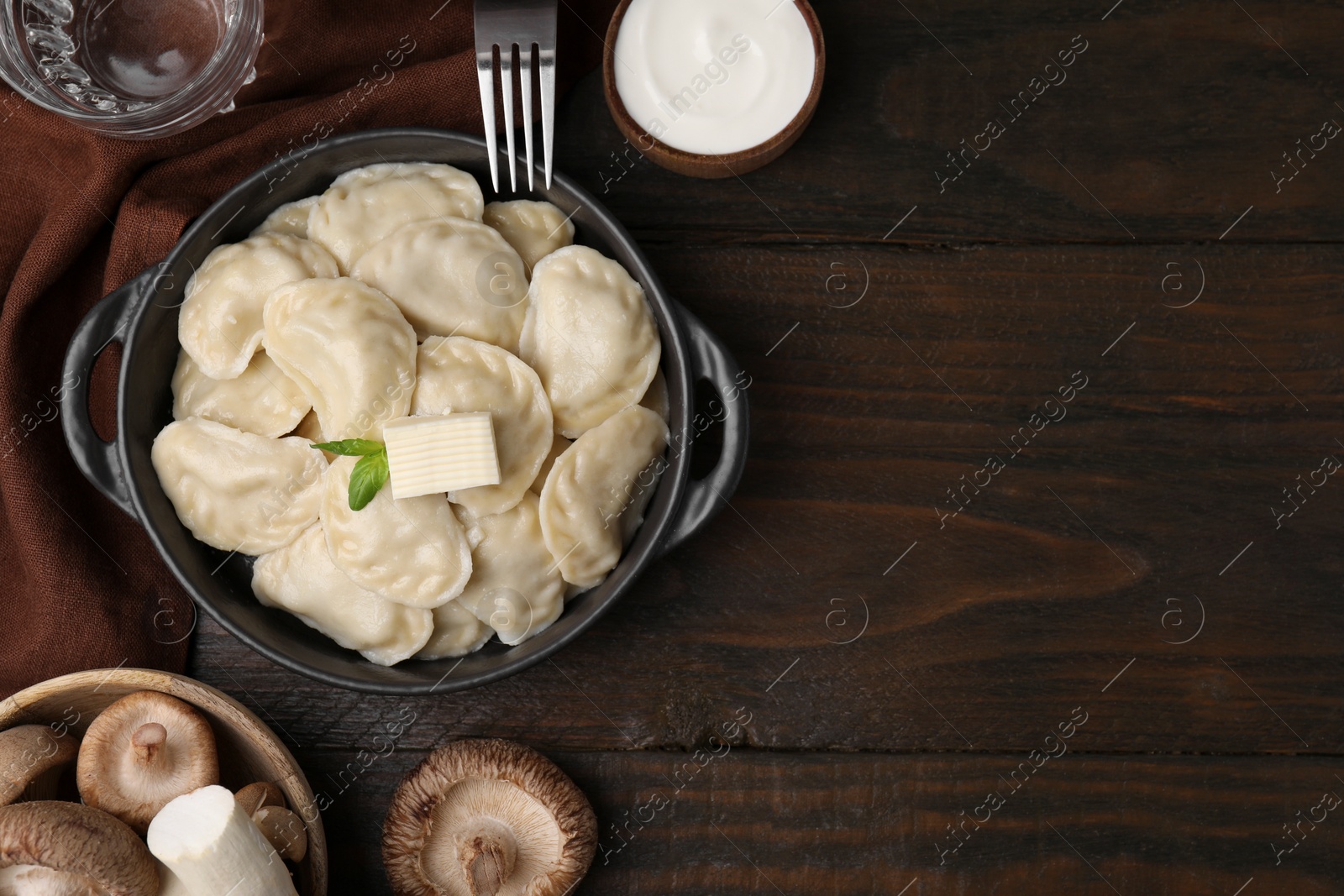 Photo of Serving pan of delicious dumplings (varenyky) with mushrooms on wooden table, flat lay. Space for text