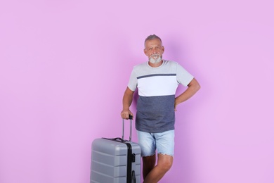 Photo of Senior man with suitcase on color background. Vacation travel