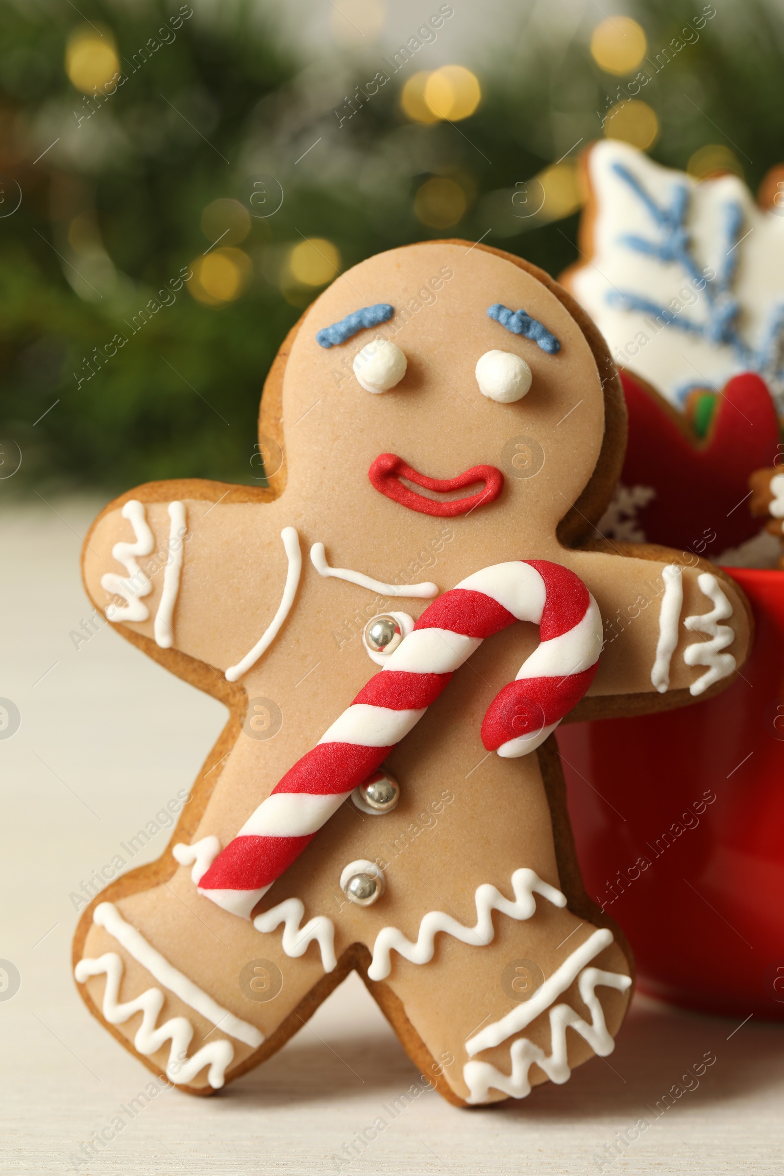 Photo of Gingerbread man and delicious homemade Christmas cookies on white wooden table against blurred festive lights