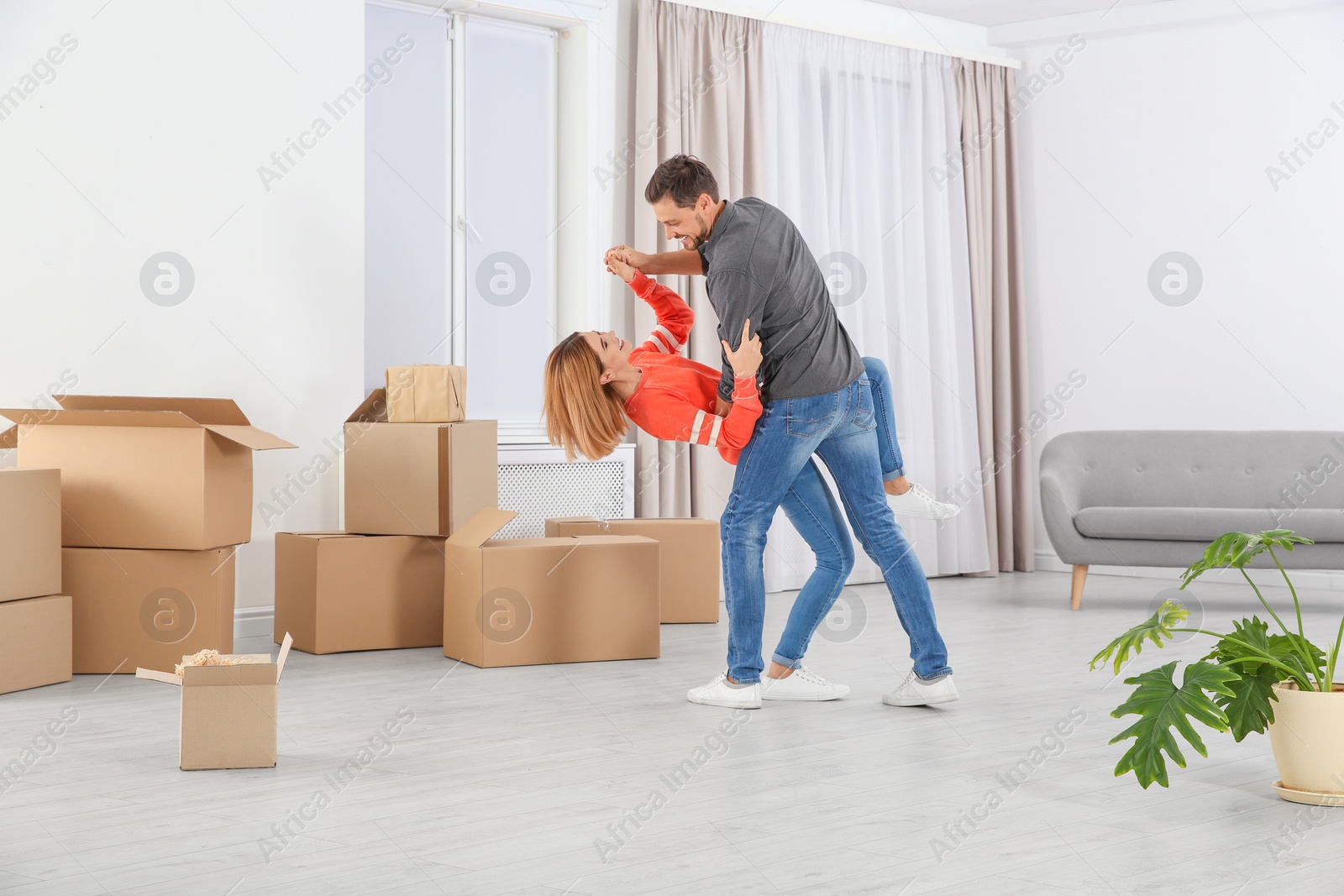 Photo of Happy couple dancing near moving boxes in their new house