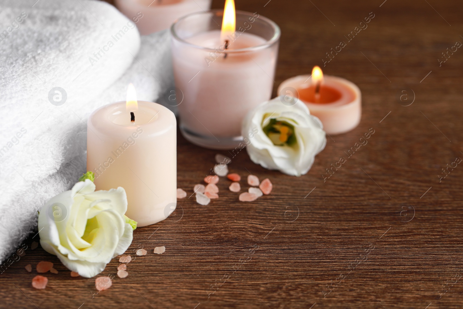 Photo of Beautiful spa composition with burning candles and flowers on wooden table. Space for text