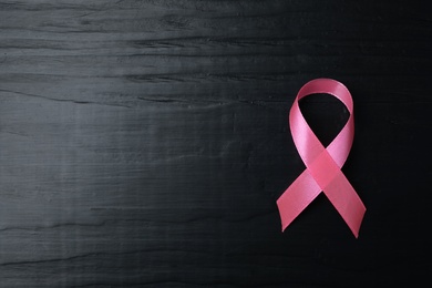 Photo of Pink ribbon on wooden background, top view with space for text. Breast cancer concept