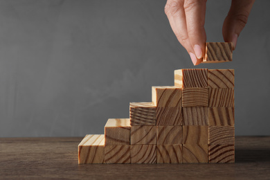 Photo of Closeup view of woman building steps with wooden blocks at table, space for text. Career ladder