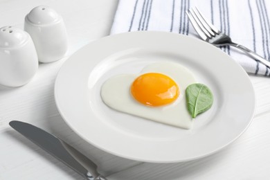 Photo of Romantic breakfast with heart shaped fried egg on white wooden table, closeup