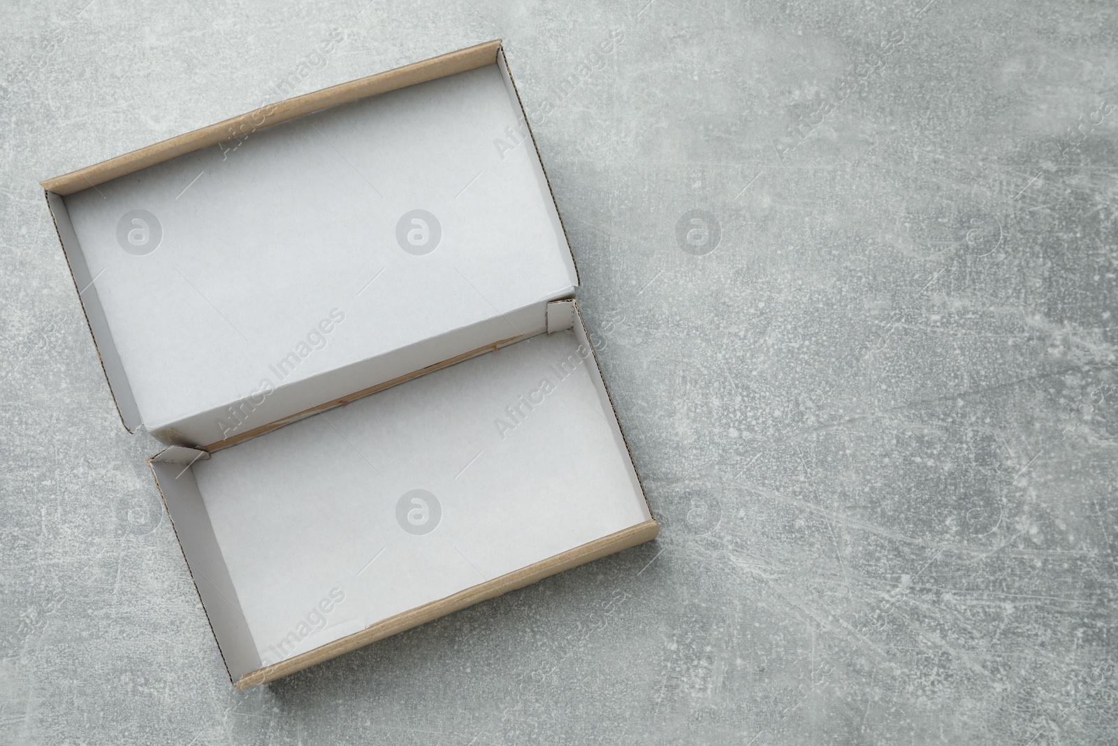 Photo of Empty open cardboard box on grey table, top view. Space for text