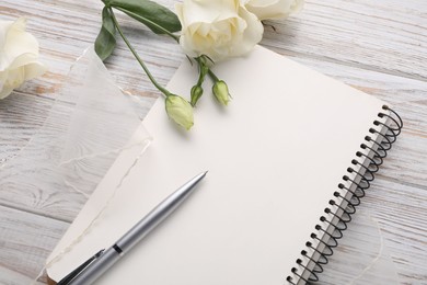 Photo of Guest list. Notebook, pen, rose flowers and ribbon on wooden background, above view