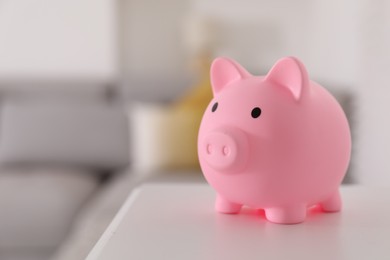 Photo of Pink piggy bank on white table, space for text