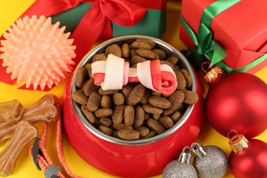 Different pet goods with Christmas gifts on yellow background, closeup. Shop assortment