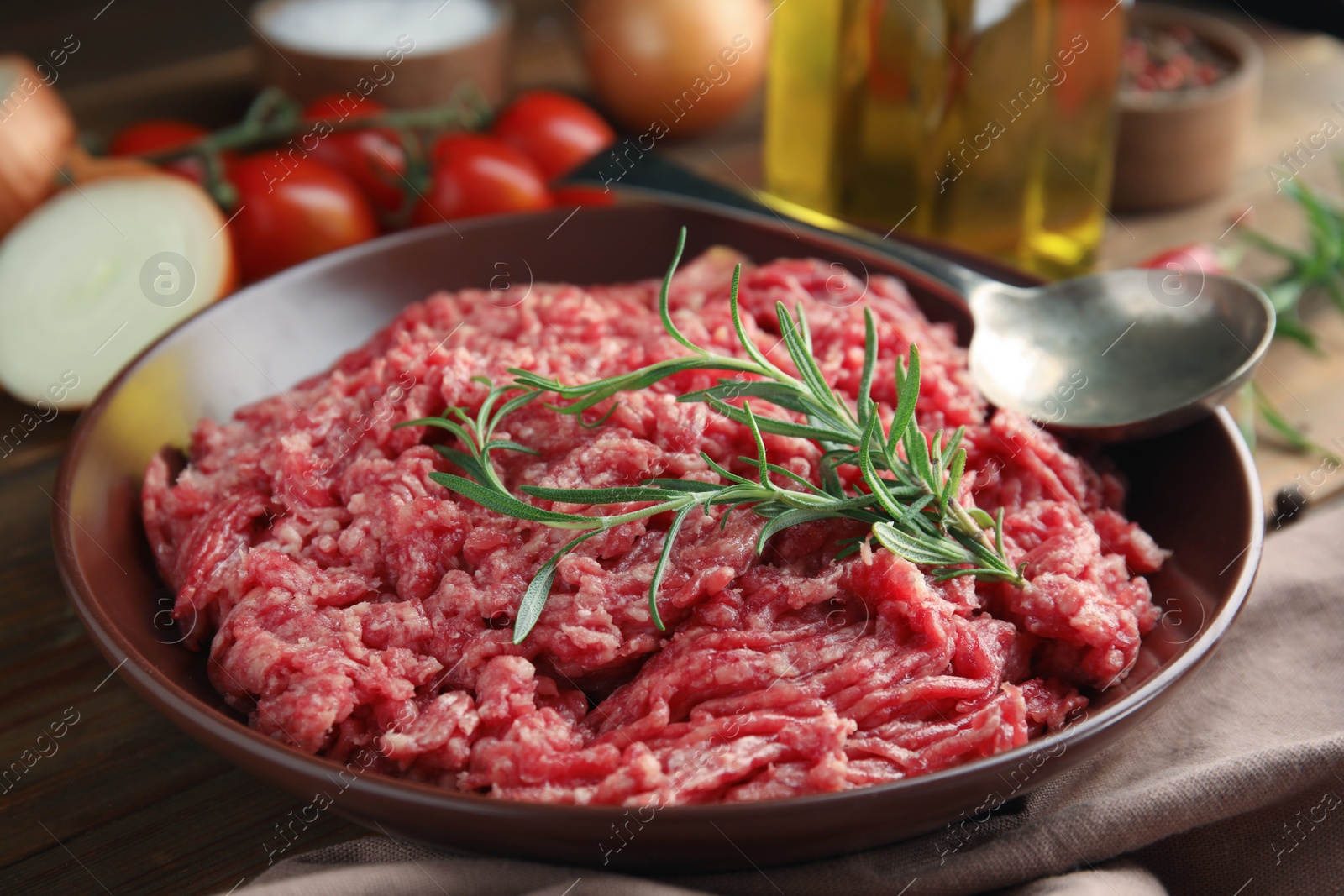 Photo of Fresh minced meat with rosemary on wooden table, closeup