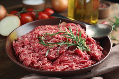 Photo of Fresh minced meat with rosemary on wooden table, closeup