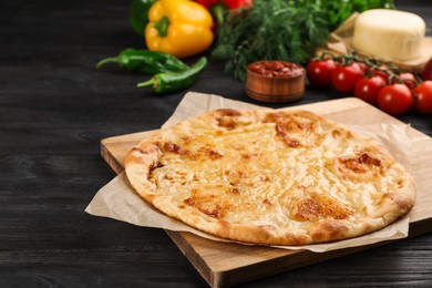 Photo of Delicious khachapuri with cheese and vegetables on dark wooden table