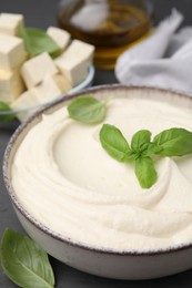 Delicious tofu sauce and basil leaves in bowl on grey table, closeup