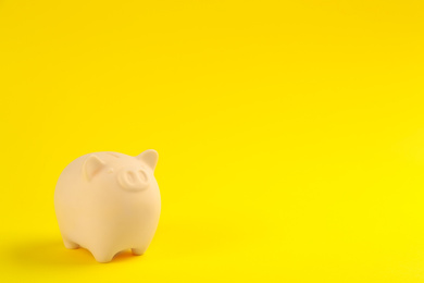 Photo of Beige piggy bank on yellow background. Space for text