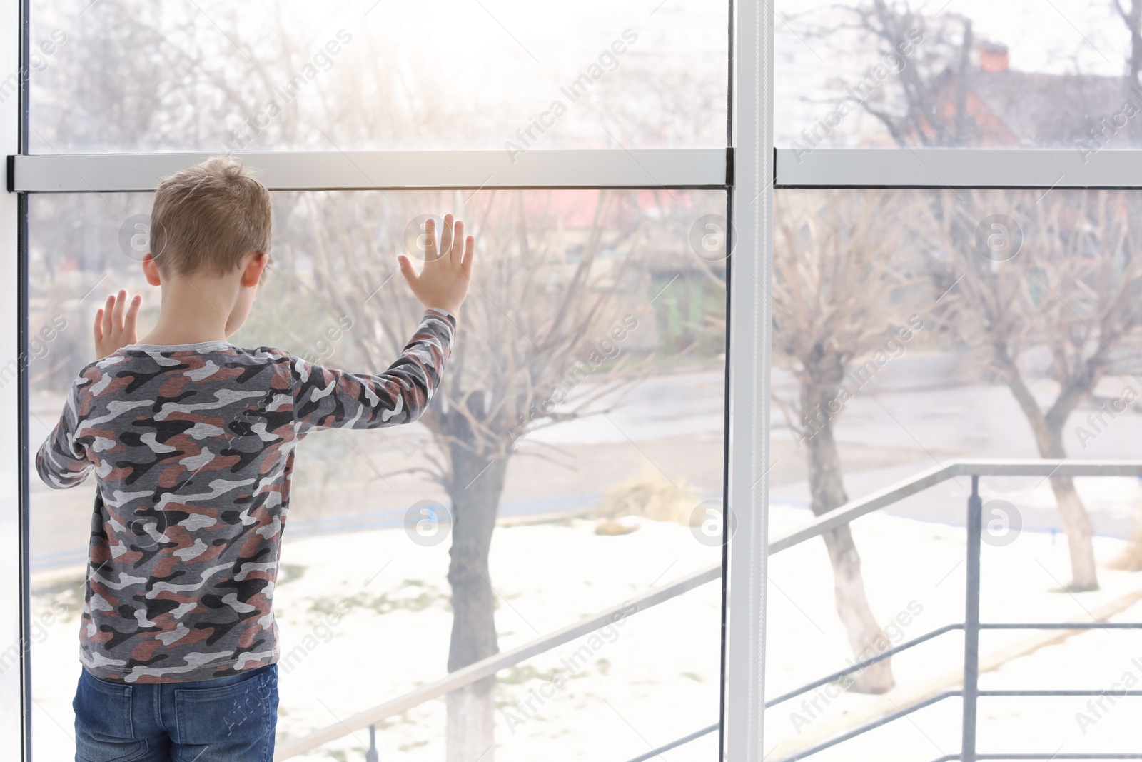 Photo of Lonely little boy near window indoors. Child autism