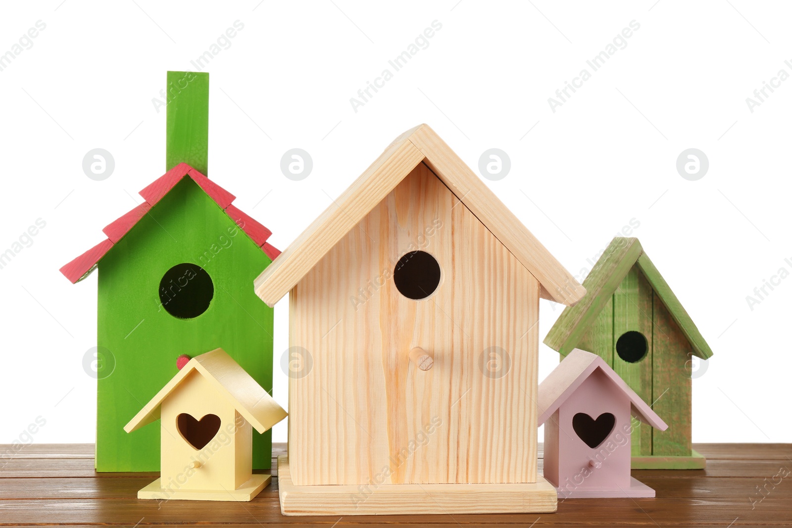 Photo of Many different bird houses on wooden table against white background