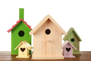 Many different bird houses on wooden table against white background