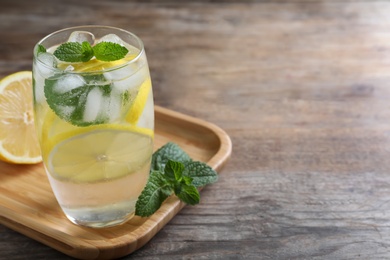 Photo of Delicious lemonade made with soda water and fresh ingredients on wooden table. Space for text
