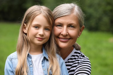 Photo of Portrait of happy grandmother with her granddaughter outdoors