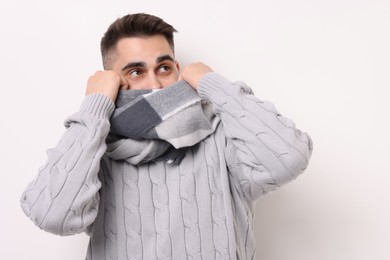 Man hiding in warm scarf on light background